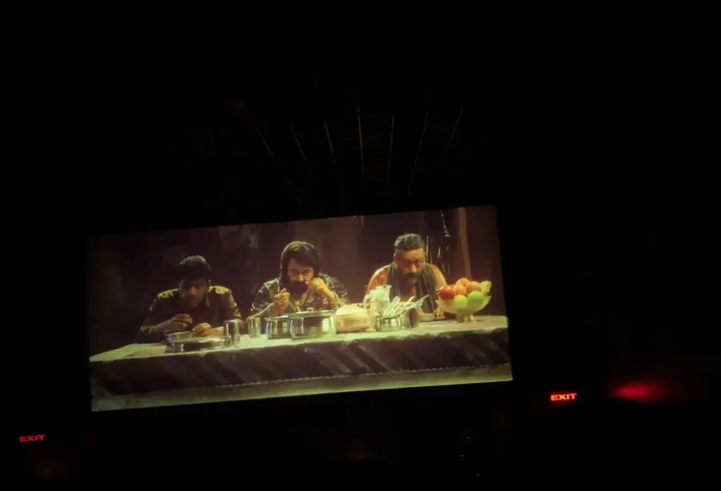Jailer 2 movie review photo showing three men eating together in a restaurant scene on the cinema screen.